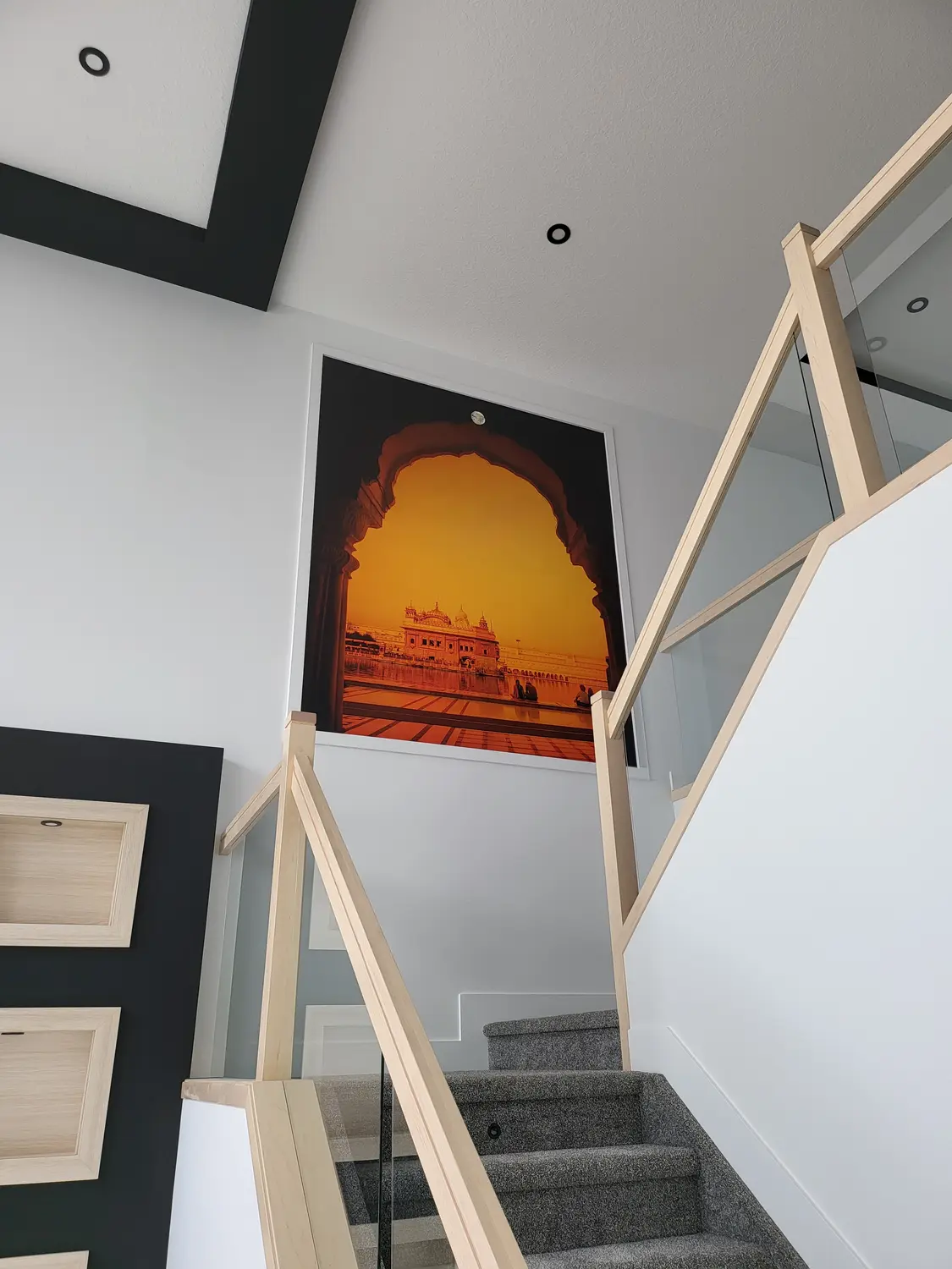 Large framed print of the Golden Temple through an arch, installed above a staircase